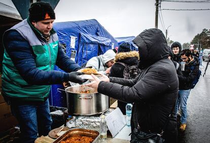 Un voluntario rumano sirve comida caliente a los refugiados que huyen del conflicto de la vecina Ucrania en el paso fronterizo de Siret, en Rumania. Un total de 113.100 ciudadanos ucranios han entrado a Rumania tras huir de la invasión rusa de su país desde que el Kremlin ordenara el pasado jueves una ofensiva militar a gran escala contra la exrepública soviética, según datos publicados por la Policía de Frontera rumana.