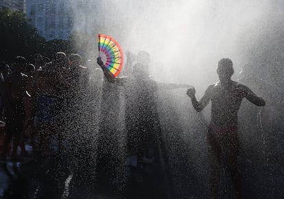 Bomberos rocían agua para refrescar a la gente mientras esperan el arranque del concierto.