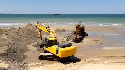 Unas máquinas excavadoras retirando arena de la playa de en Cádiz, en Andalucía.