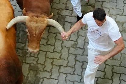Un mozo sujeta el asta de uno de los toros de la ganadería de Domingo Hernández Martín, de El Palancar de Traguntía (Salamanca), este jueves, durante el quinto encierro de San Fermín. 
