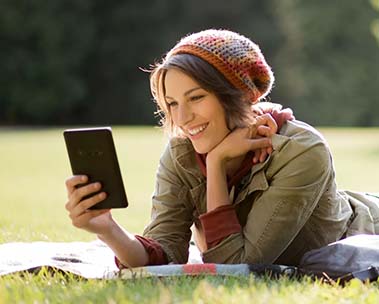 Junge Frau liest ihren Amazon-Kindle im Gras
