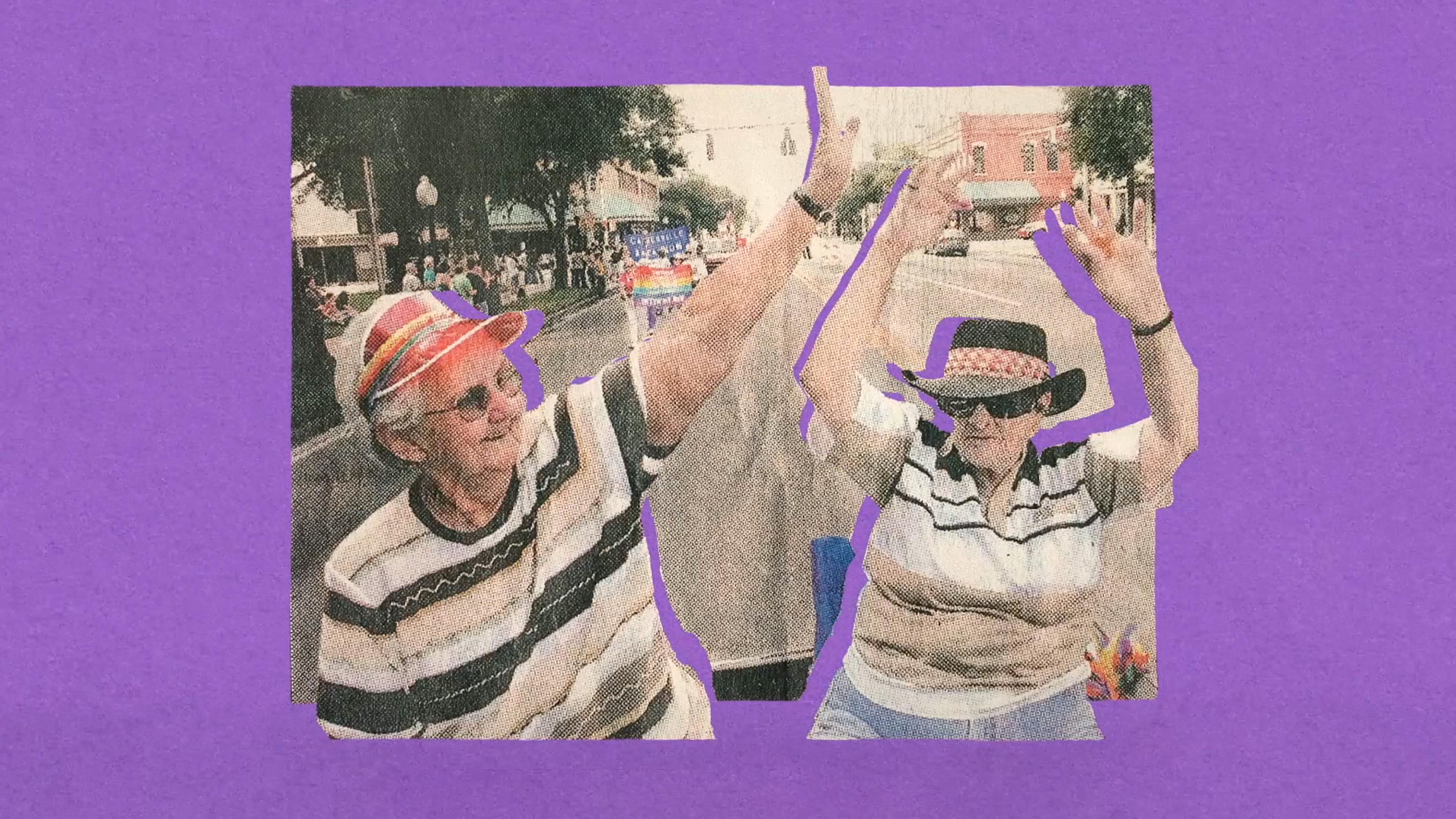 Two older women wearing hats and sunglasses raise their arms in celebration at a street parade, with a purple background.