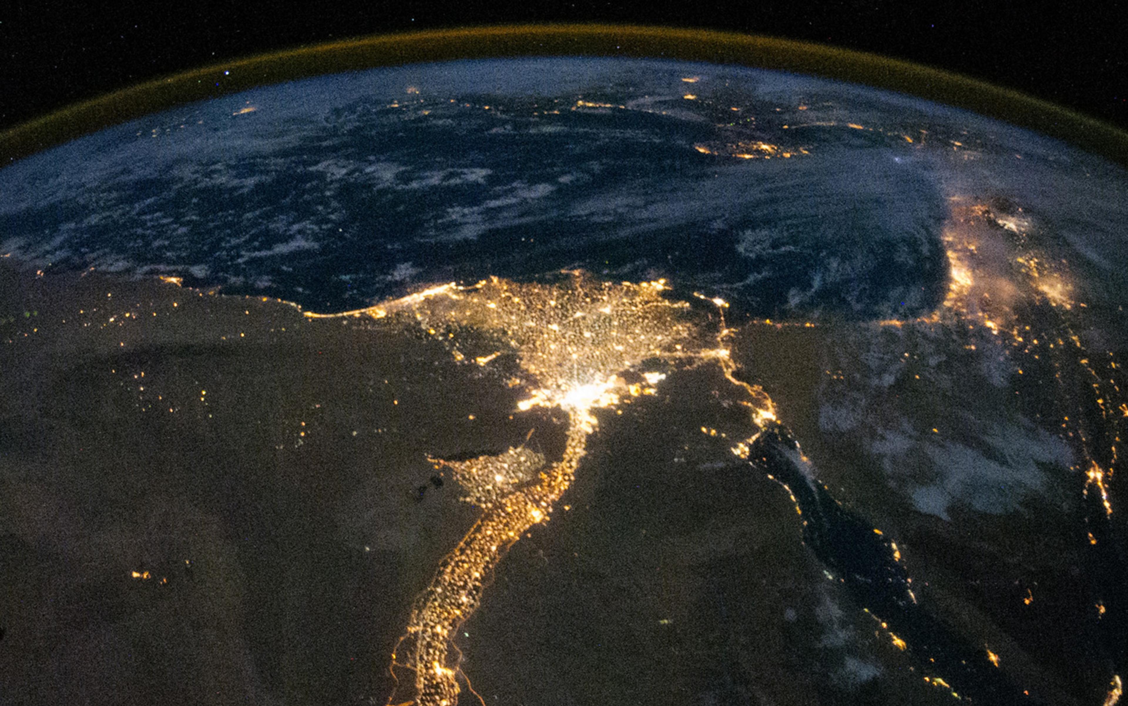 Satellite image of planet Earth at night showing the Nile River illuminated with city lights surrounded by darkness.