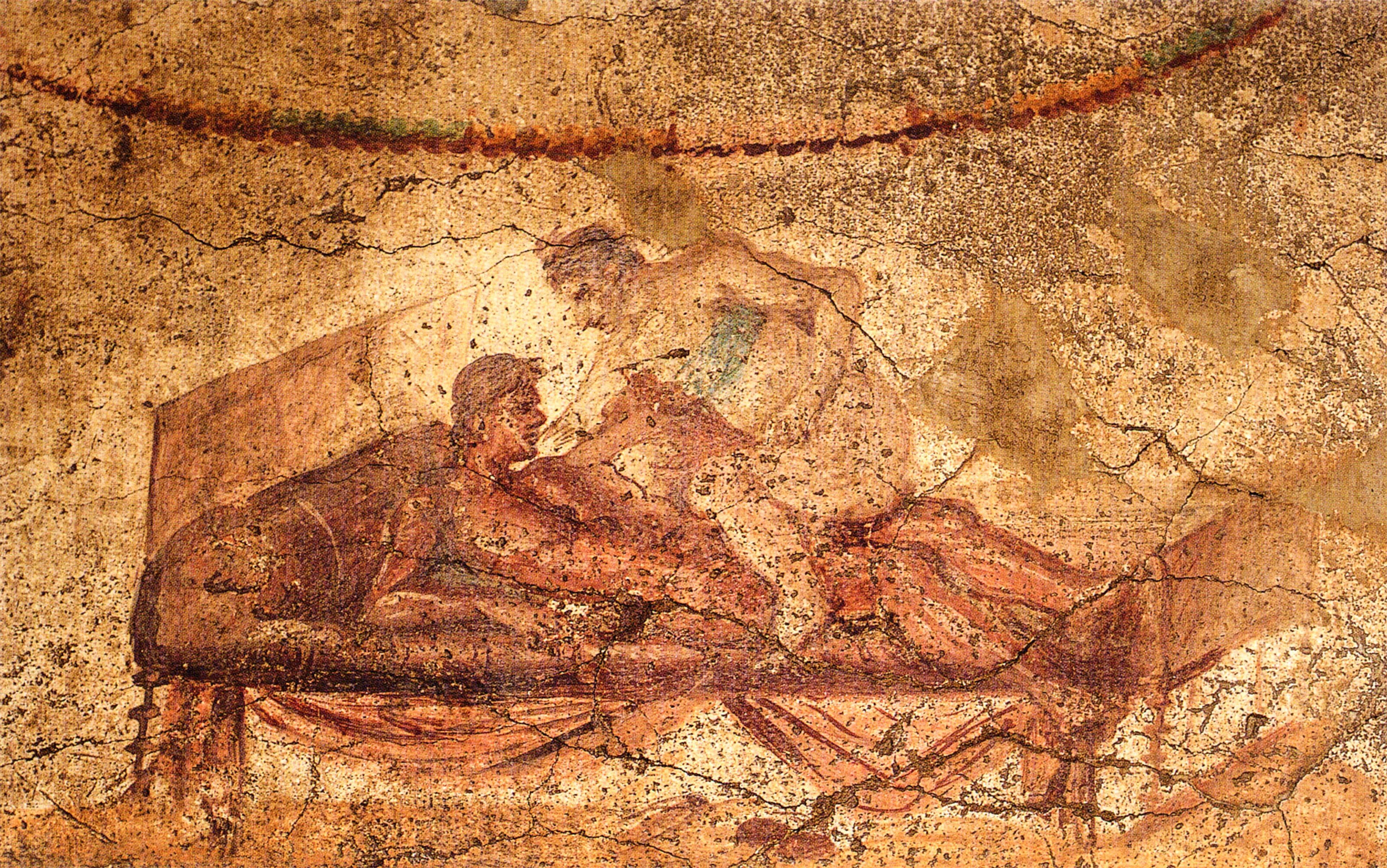 Ancient Roman fresco depicting two figures engaging in an intimate moment on a bed, with a background of earthy tones and visible cracks in the surface.