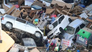 Des personnes grimpent sur des voitures empilées à la suite des inondations à Sedavi, au sud de Valence, dans l'est de l'Espagne, le 30 octobre 2024.