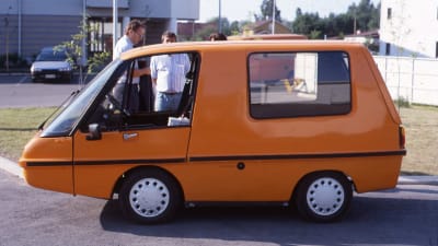 Oranssi Finnvan-sähköauto parkkeerattuna asfalttikadun varteen.