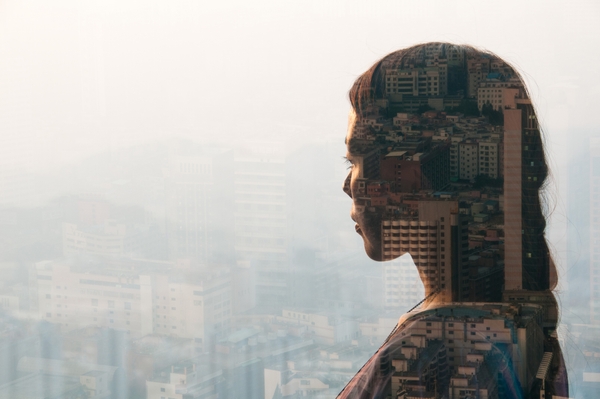 A female business employee thinking about business communication while looking at buildings outside through the glass.