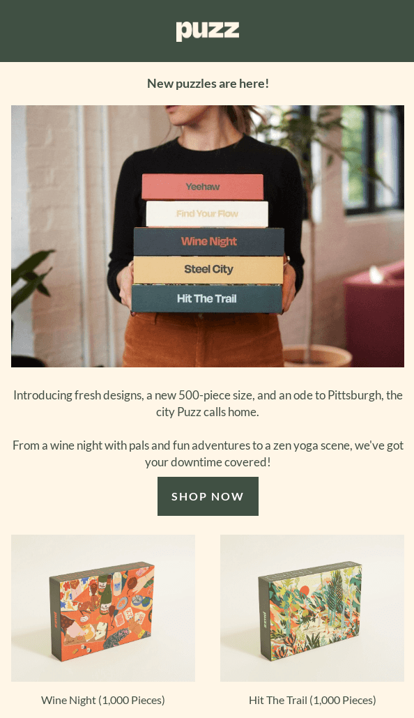 New product launch email from puzz with the heading New puzzles are here! and showing the image of someone holding a stack of several boxes of puzzles.