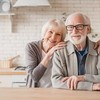 Portrait of caucasian smiling senior old elderly couple family spouses grandparents looking at camera, embracing hugging with love and care at home kitchen