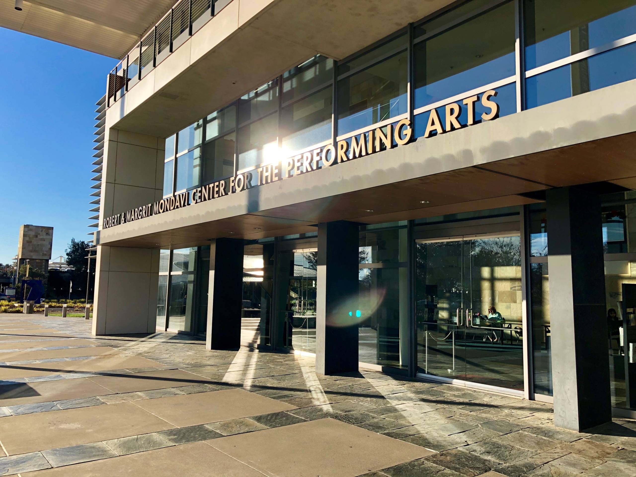 Outside the Mondavi Center during the day with the sun reflecting off the title of the venue