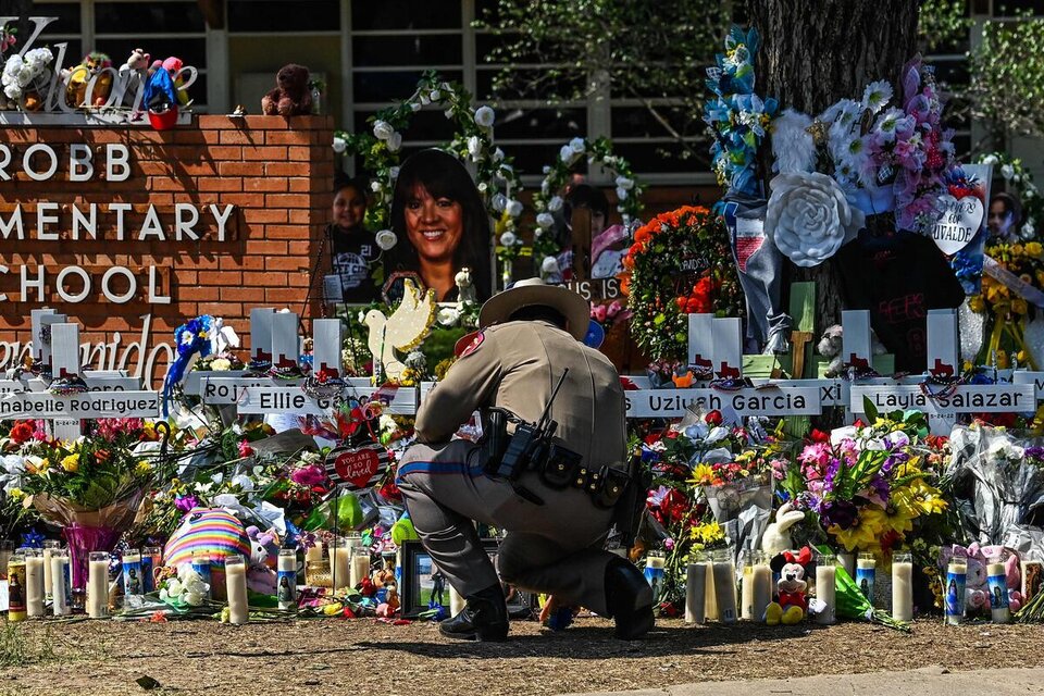 Un oficial de policía limpia el memorial improvisado en la escuela primaria Robb en Uvalde, Texas. (Fuente: AFP)