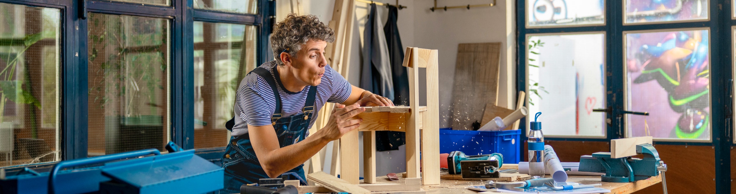 Timmerman blaast stof van een kinderstoeltje