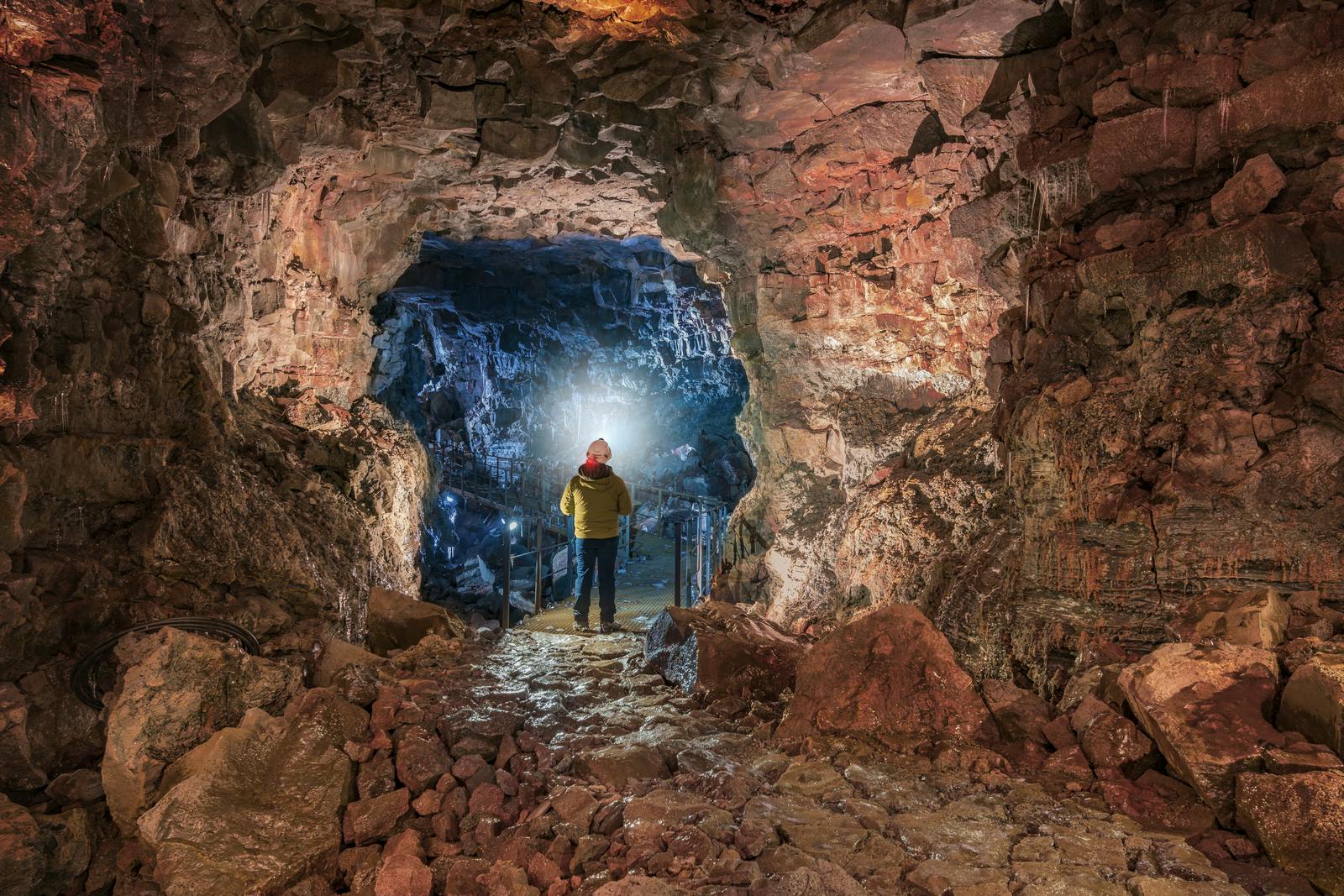 A man inside a lava tube cave with red walls