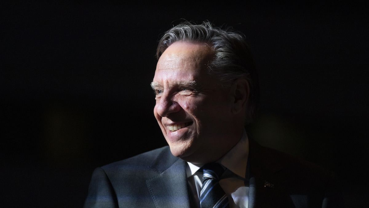 François Legault, dans l'ombre, regarde vers la gauche.