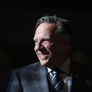 François Legault, dans l'ombre, regarde vers la gauche.