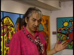 Norval Morrisseau et tableaux en arrière-plan. 