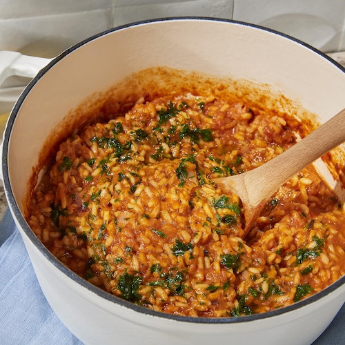 Une casserole remplie de risotto végétalien tomate grillée et harissa.