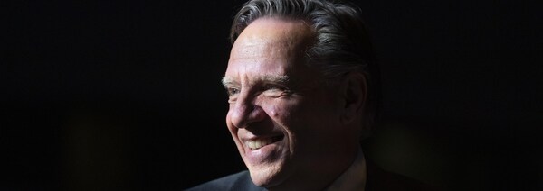 François Legault, dans l'ombre, regarde vers la gauche.