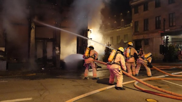 Plusieurs pompiers en train d'éteindre un feu dans le Vieux-Montréal. 