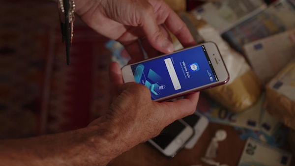 Un homme tient dans ses mains un cellulaire qui affiche la messagerie SKY.