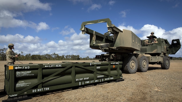 Un artilleur prépare la grue pour le chargement du système de missiles tactiques de l'armée sur le dispositif de roquettes d'artillerie à haute mobilité.