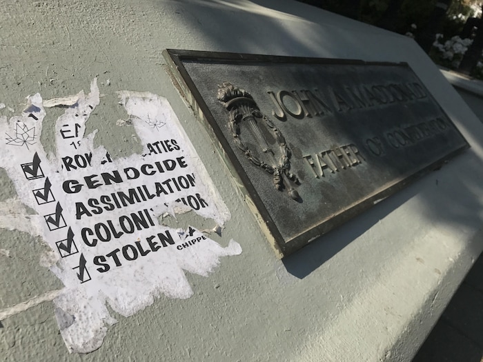 Une affiche a été collée sur la statue de John A. Macdonald dans le parc Victoria à Regina. L'affiche mentionne des mots comme : « génocide », « assimilation », et « colonisation ».