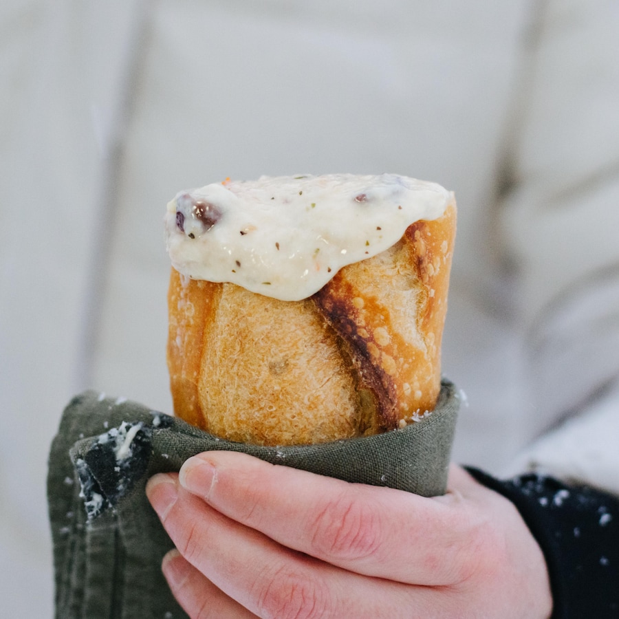 Une main tient une fondue au fromage dans une baguette.