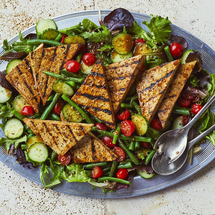 Grand plat de salade d'été avec tofu grillé, concombres, tomates et fèves vertes. 