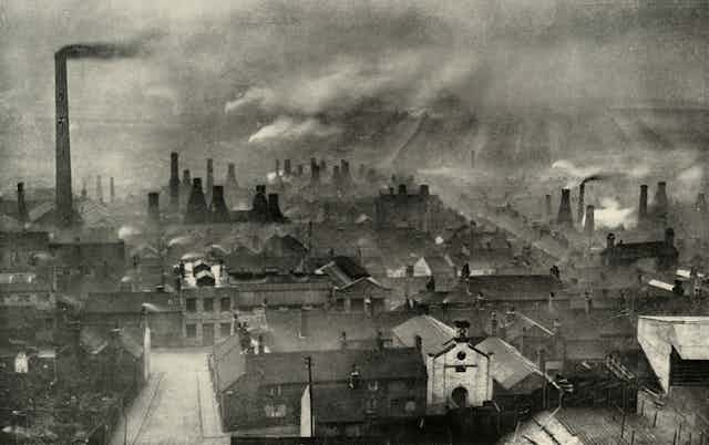 Smoke rises from many chimneys in an industrial area of England.