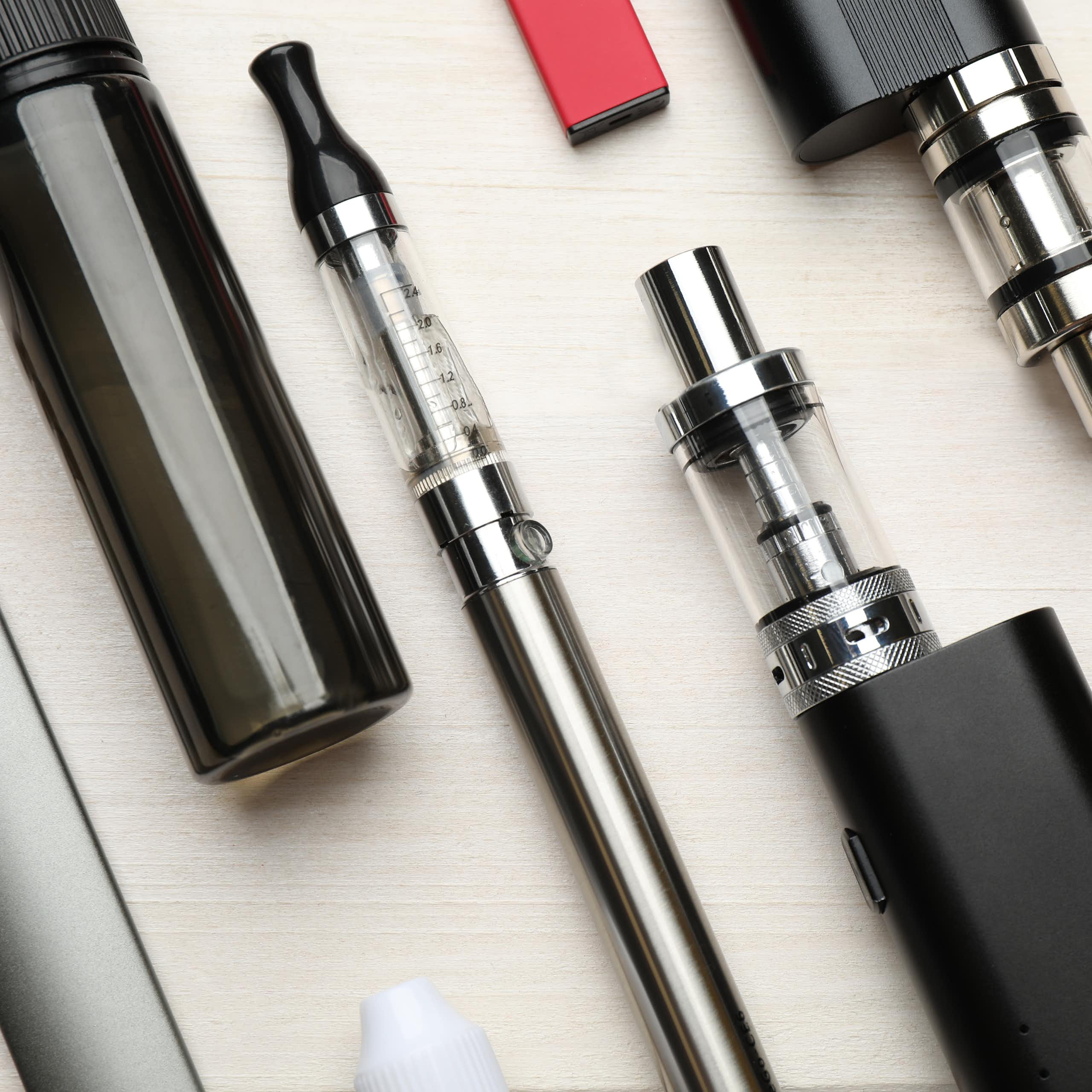 A variety of e-cigarette products lying flat on a white surface.