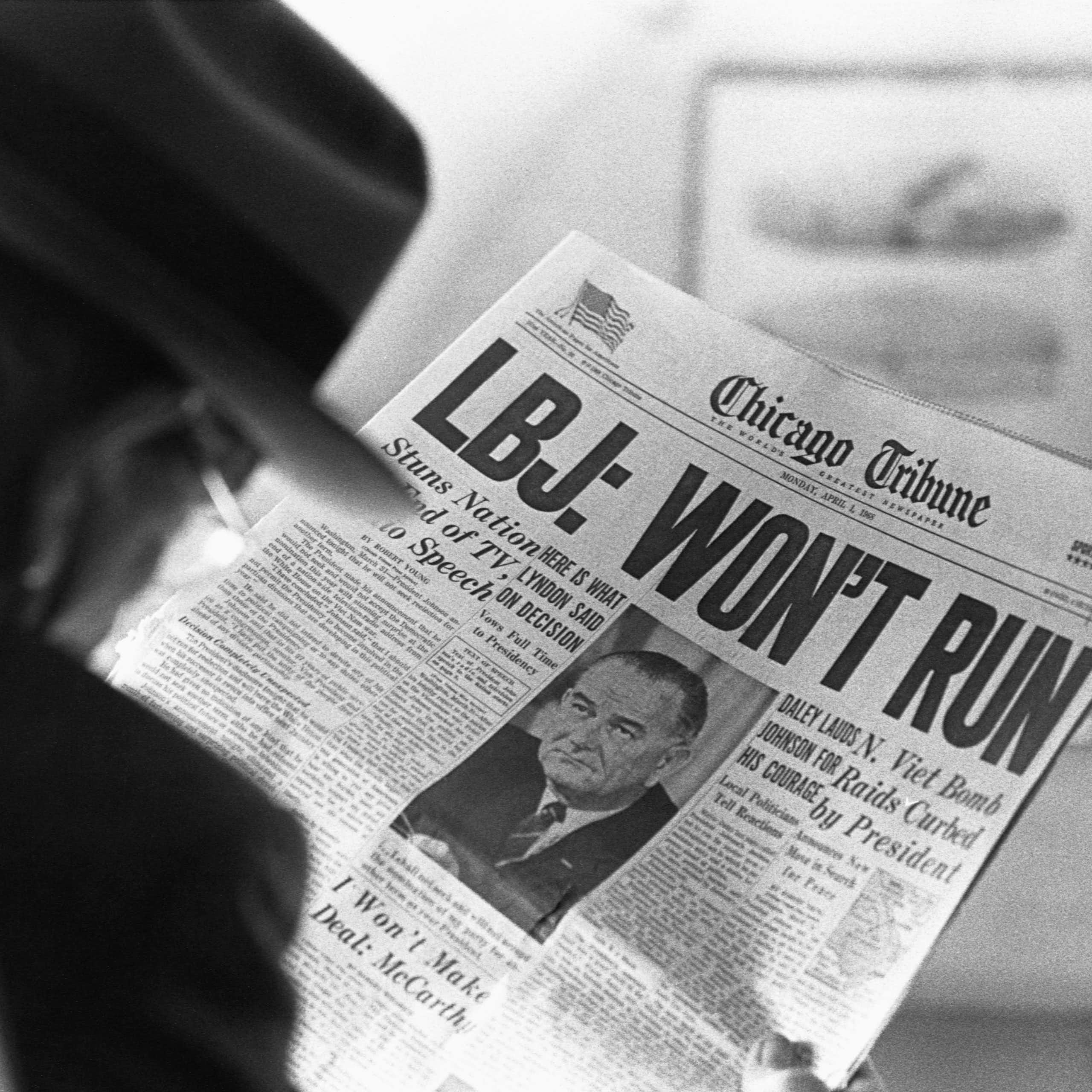 A man is reading a newspaper headline that says LBJ won't run in very large letters.