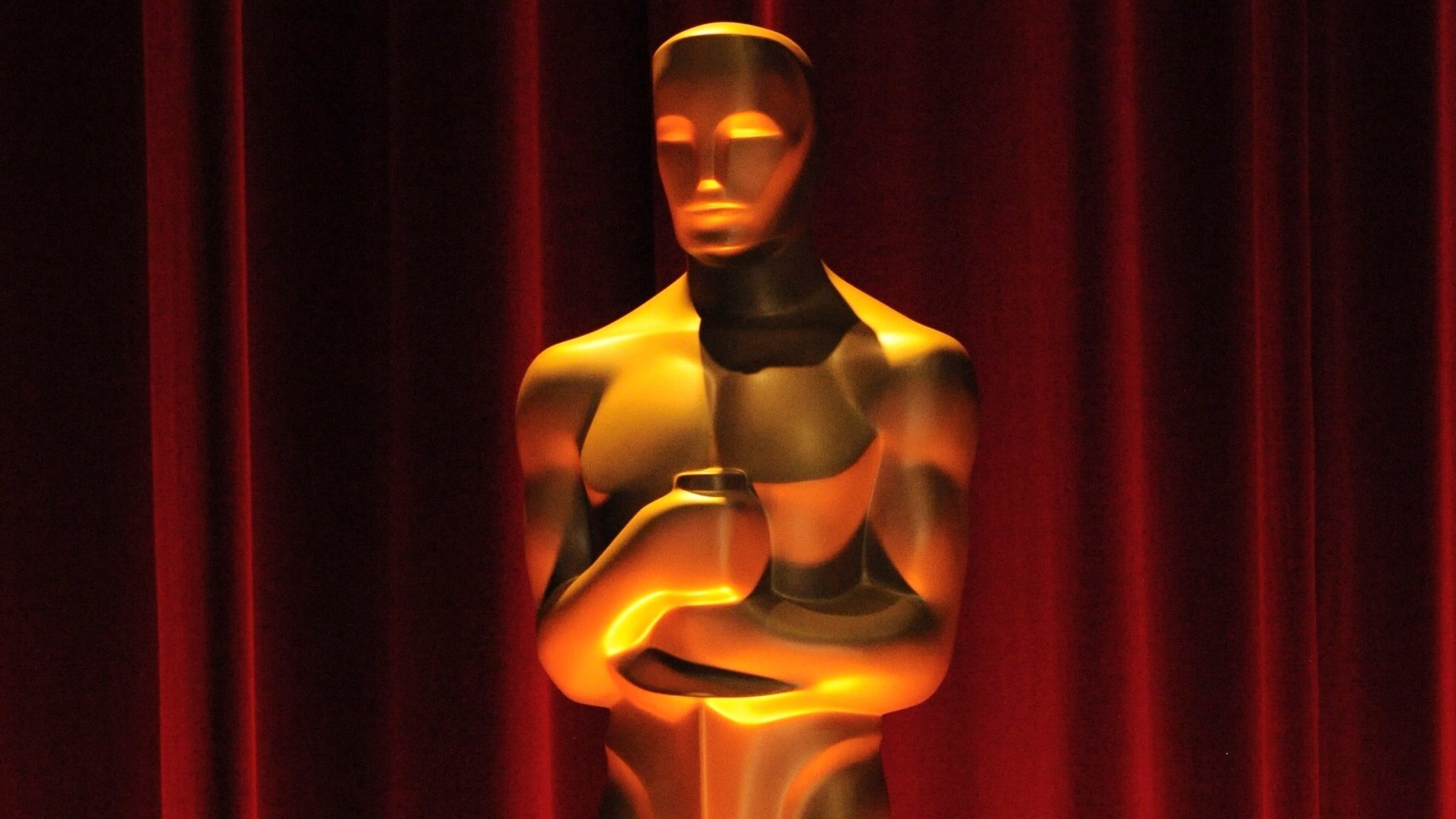 Eine von oben beleuchtete Oscar-Statue vor einem rotem Vorhang