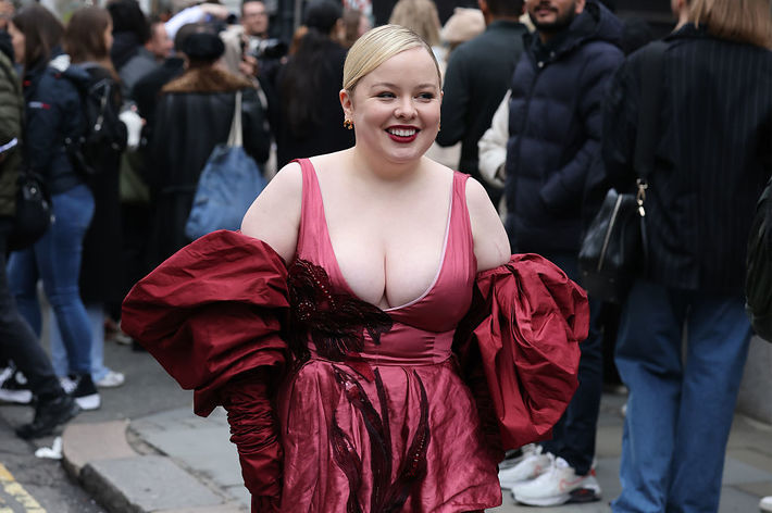 Woman in a red dress with voluminous sleeves walking on a street, smiling