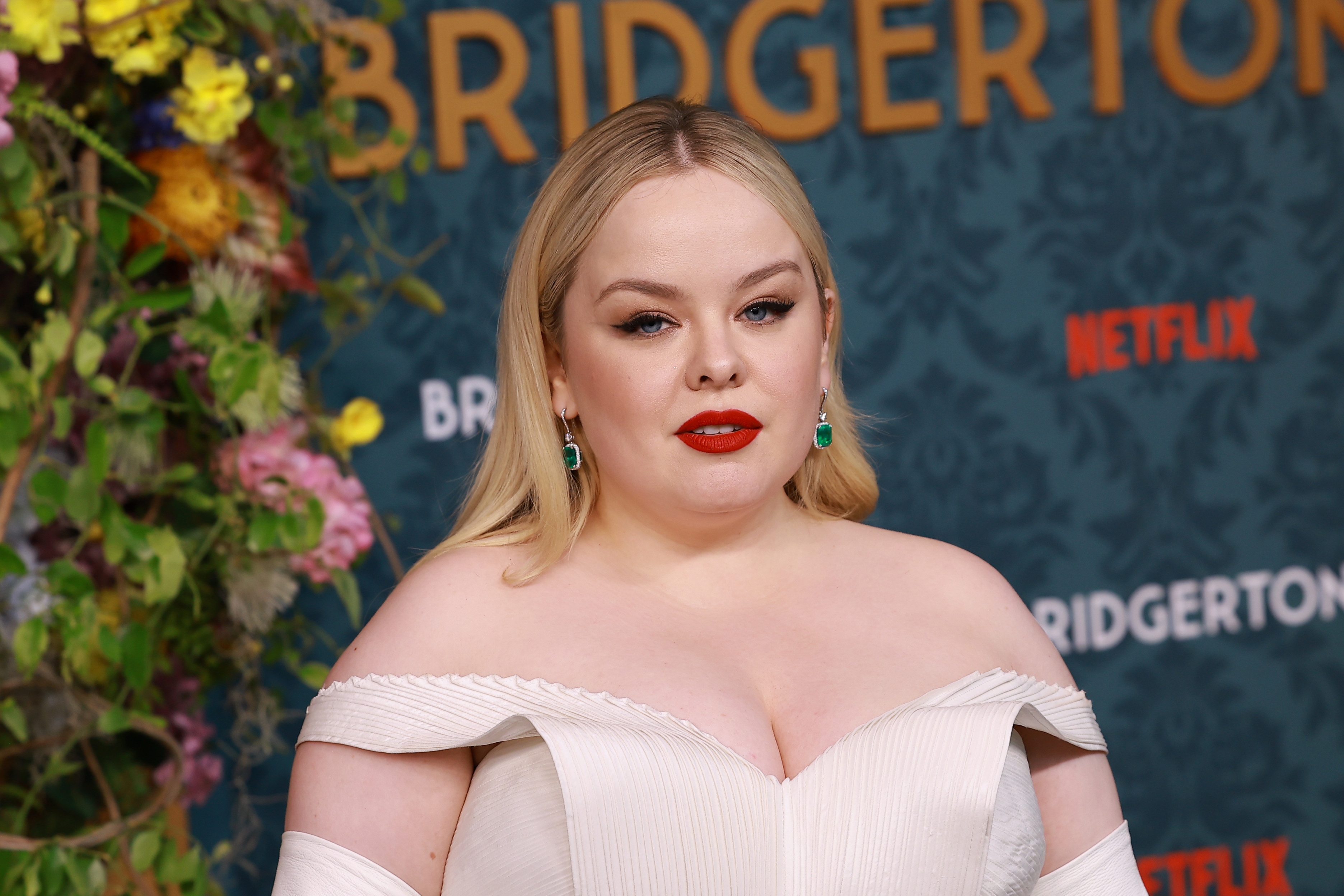 Nicola Coughlan in off-shoulder gown posing at Bridgerton event