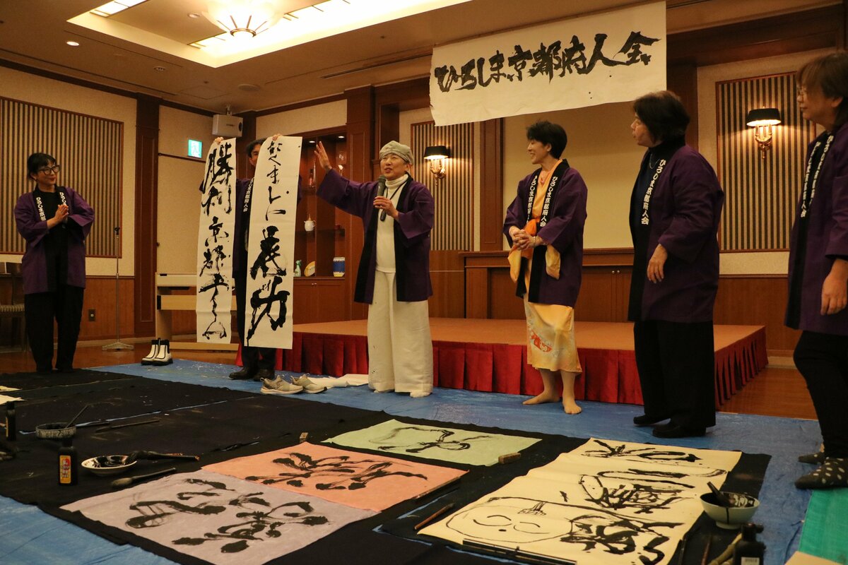 駅伝応援に向け、仲間たちとしたためたアート書道を紹介する京都府人会の小川さん(左から3人目)