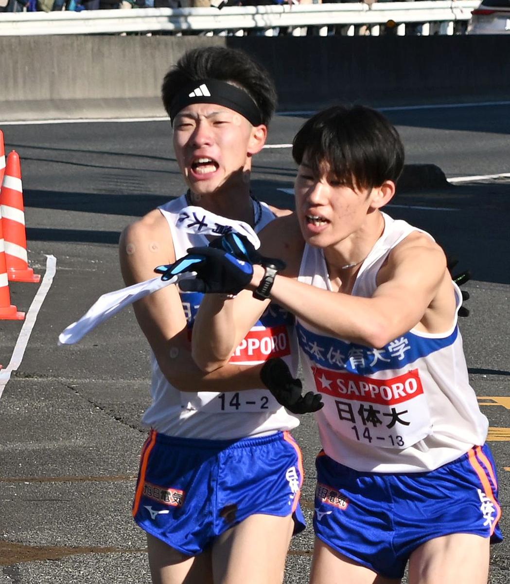 ２区を走り、たすきを渡す日体大の山崎丞（左）＝横浜市戸塚区