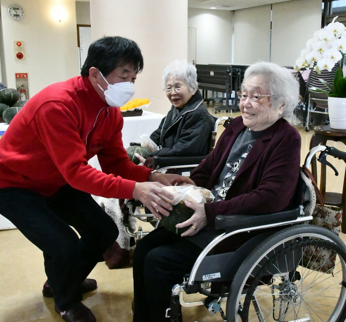 住田組合長㊧からカボチャとユズを受け取る森永さん㊨と山村さん