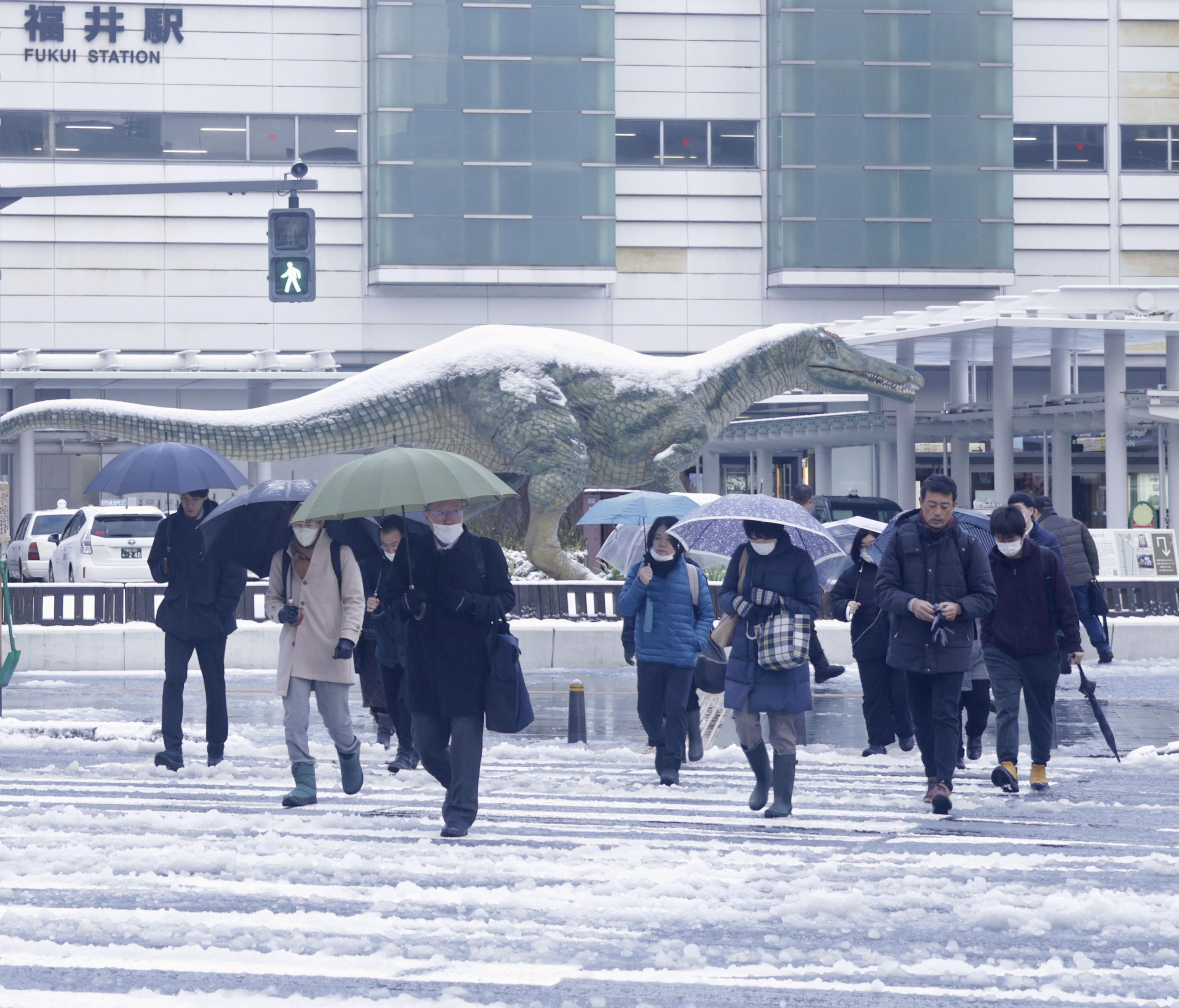 積雪した福井駅前を歩く人たち＝9日午前、福井市