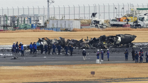 日航機と衝突し、焼け焦げた海上保安庁の航空機の周辺に集まる警視庁の捜査員や東京消防庁の隊員ら＝２０２４年１月３日、羽田空港