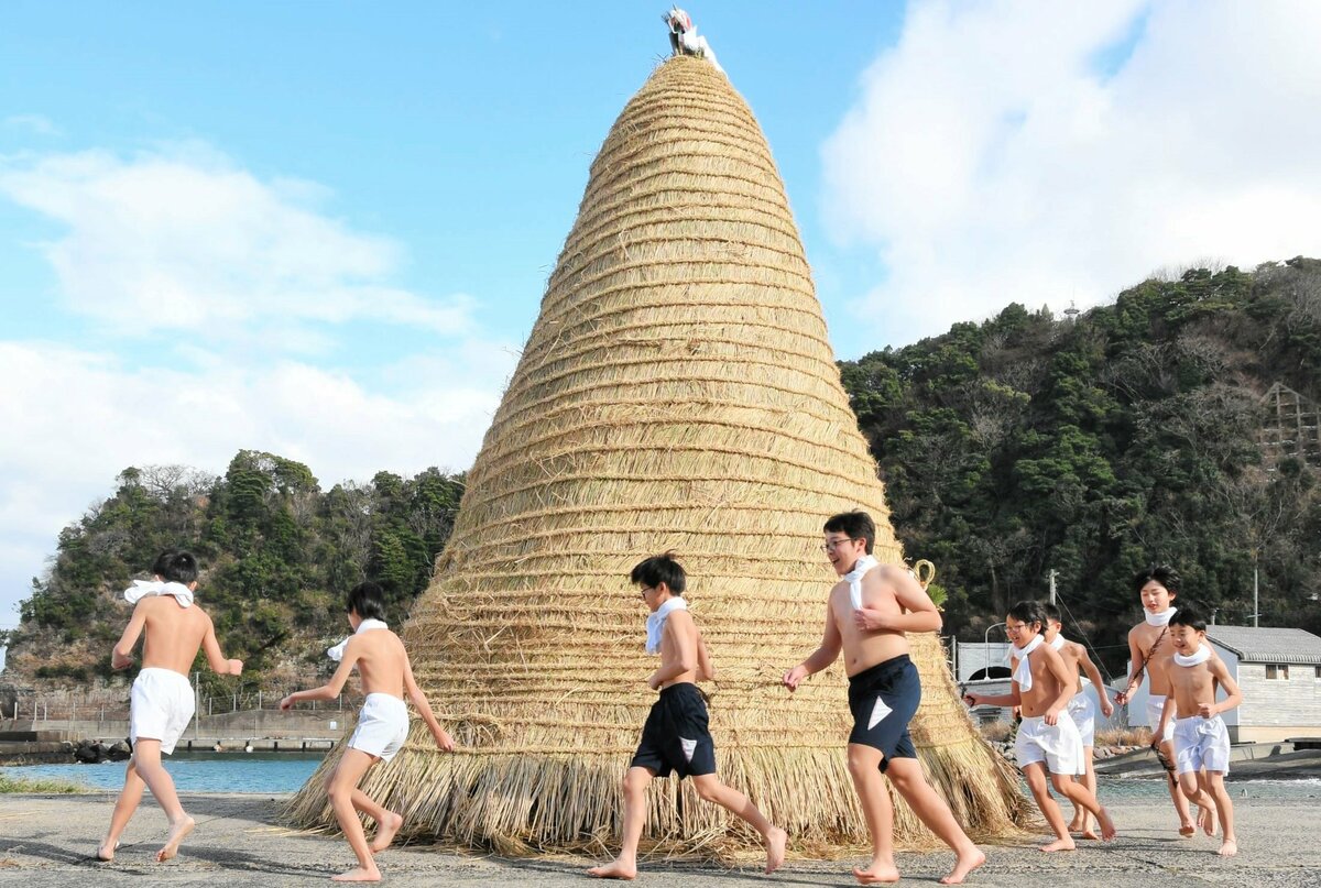 無病息災を祈って巨大なトンドウの周りを走る男児ら＝１１日、鳥取市気高町酒津の酒津漁港