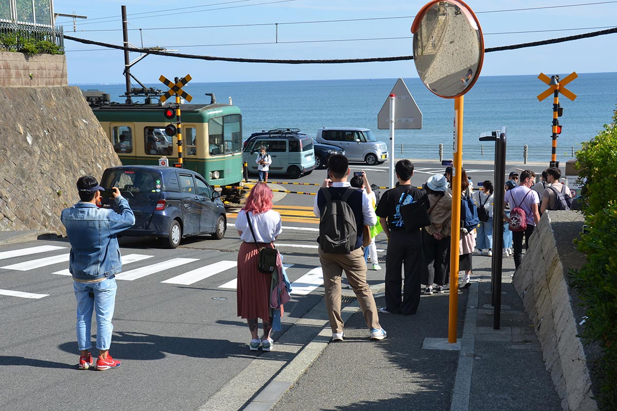 鎌倉高校前駅近くの踏切で江ノ電を撮影する外国人観光客ら＝鎌倉市腰越１丁目