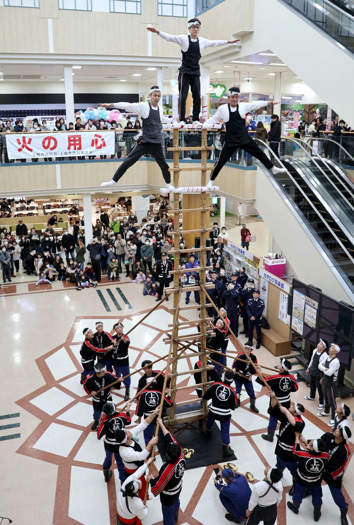 伝統のはしご登りを披露する上越市消防団板倉方面隊の団員＝１月１２日、上越市富岡のイオン上越店