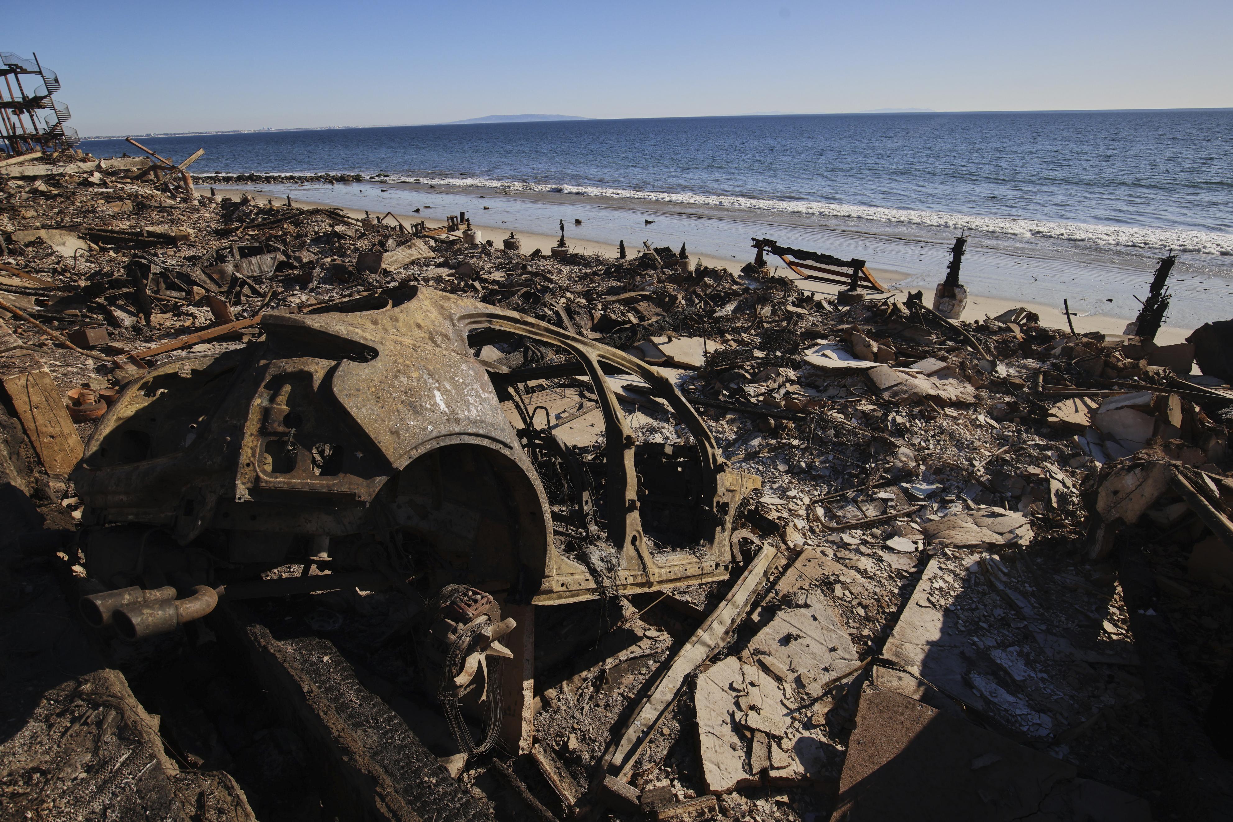 14日、米カリフォルニア州で、山火事により焼損した住宅や車の残骸（AP＝共同）