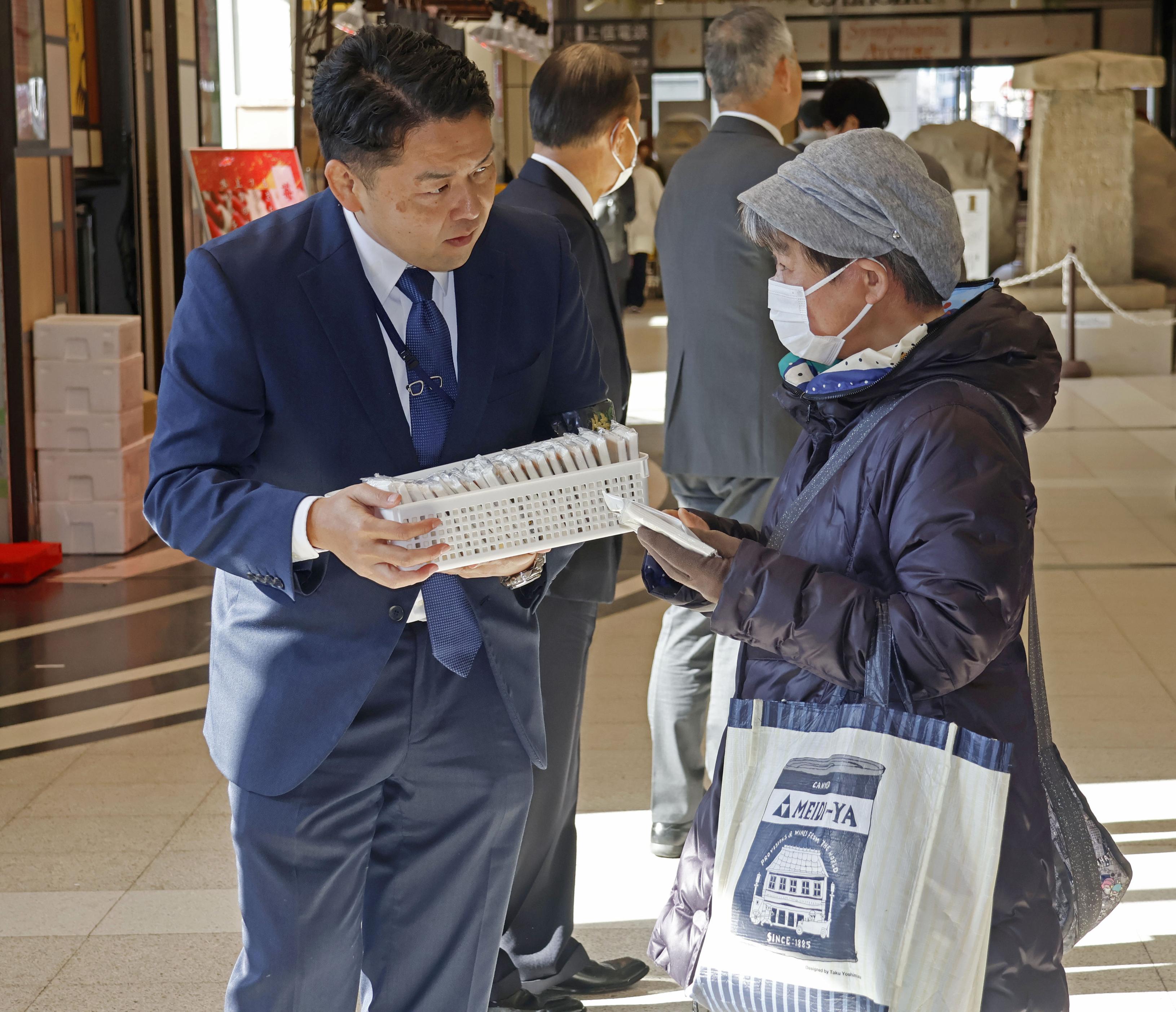 情報提供を求め、ポケットティッシュを配る群馬県警の警察官（手前左）＝14日午前、群馬県高崎市