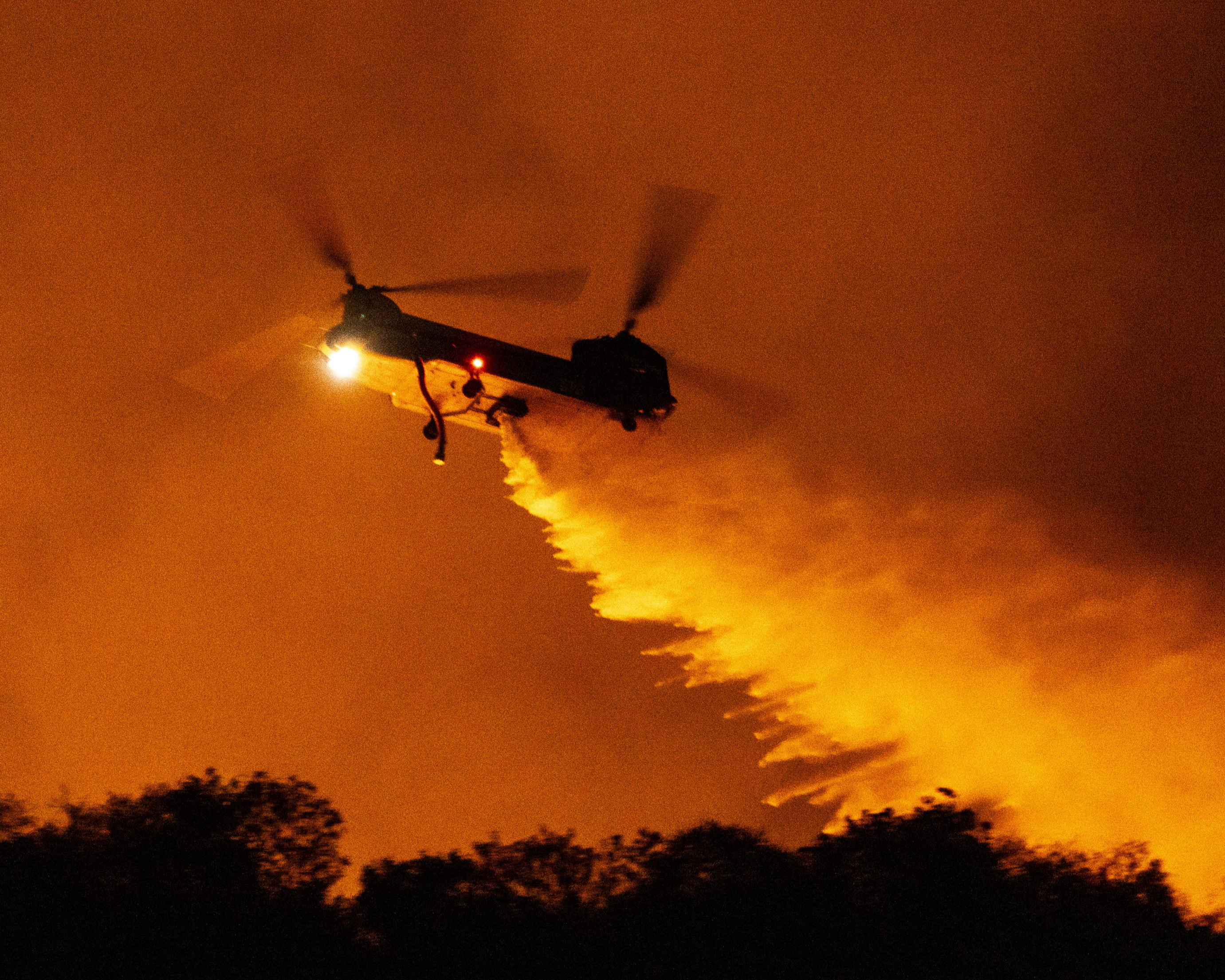 米カリフォルニア州ロサンゼルスの山火事で水を投下するヘリコプター＝11日（AP＝共同）