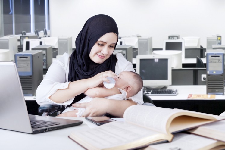 A mother feeds her child in an office environment. 