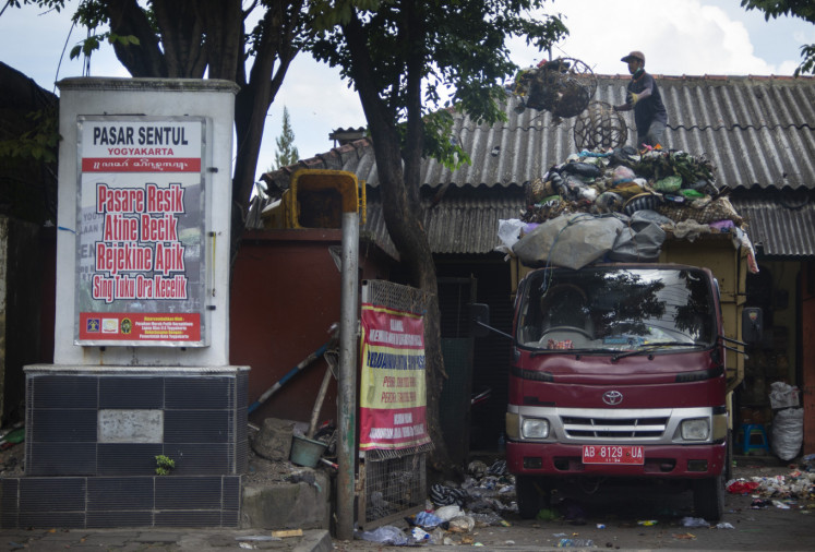 A Yogyakarta city sanitation worker loads garbage on to a truck to be taken to a landfill on April 12, 2020 in Piyungan, Yogyakarta. 