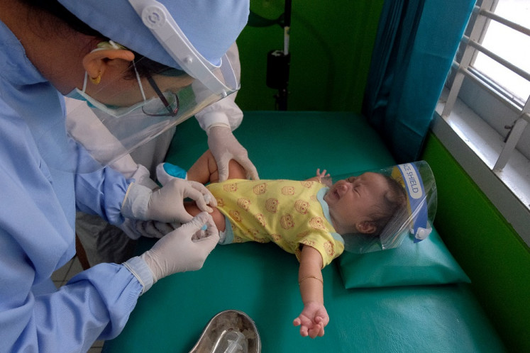 A health worker vaccinates an infant on Aug. 19 at the Puskesmas (community health center) in South Denpasar, Bali, as part of the government’s stunting prevention program.