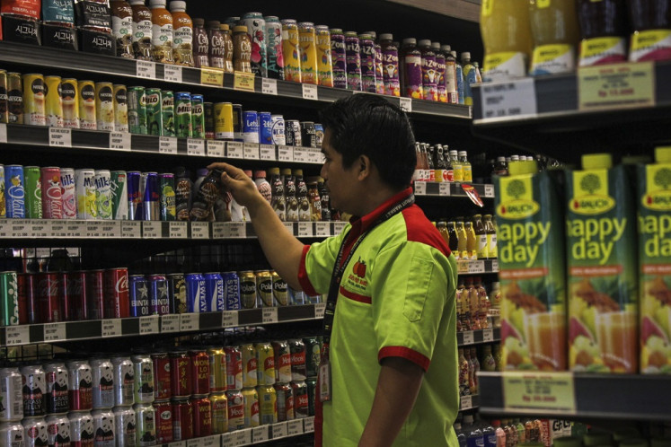 A worker arranges sugar-sweetened beverages on Dec. 14, 2023 in a supermarket in Jakarta.