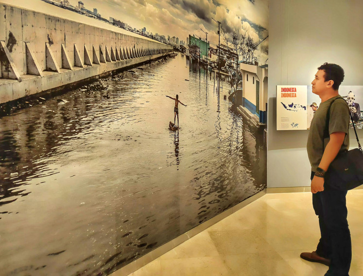 Closer to home: A man looks at a photo of the sea wall in Pluit, North Jakarta, on May 21, 2024, during a photography exhibition at theErasmus Huis in Jakarta. The photo shows how the wall has been ineffective in preventing flooded caused by rising tides. 